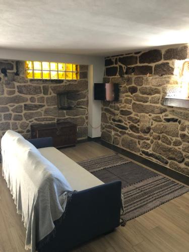 a bedroom with a stone wall with a bed and a window at Casa da Tia Balbina - Medeiros in Medeiros