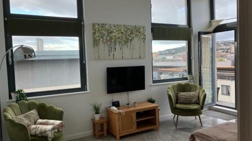 a living room with two chairs and a flat screen tv at Swansea Bay, Marina, Swansea Arena, Beach & City in Swansea
