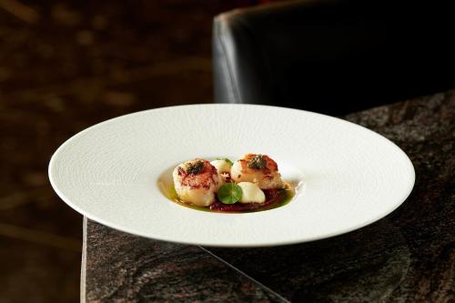 a white plate with food on a table at InterContinental Hanoi Landmark72 by IHG in Hanoi