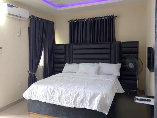 a bedroom with a large bed with a black headboard at 2 Bed - Sleeps 4 - AirCon - Free Parking in Benin City