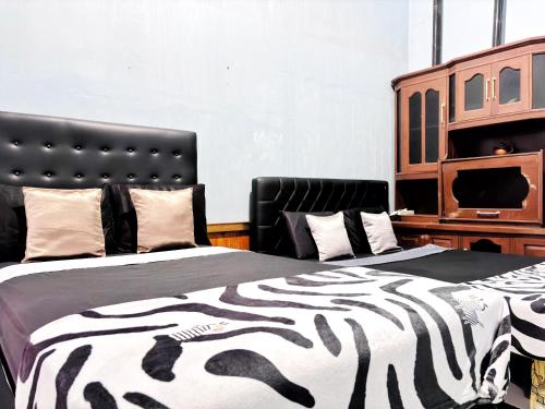 a bedroom with two beds with a zebra blanket at Kost Harian Semarang Murah in Semarang