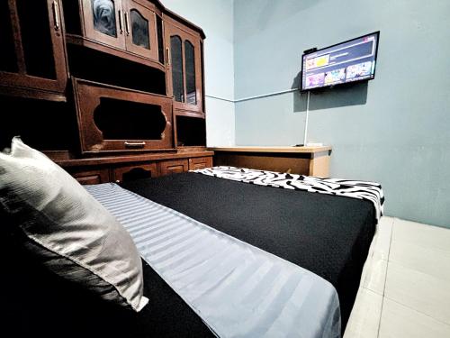 a bedroom with a bed and a flat screen tv at Kost Harian Semarang Murah in Semarang