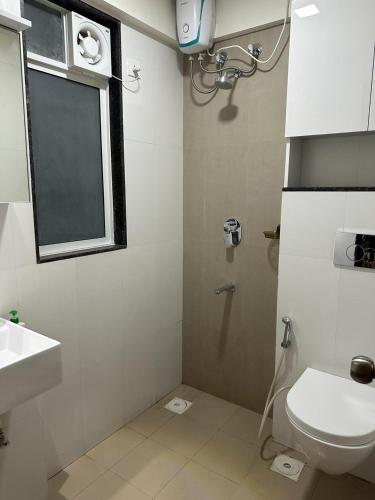 a bathroom with a toilet and a sink and a window at Residential Tranquil in Mumbai