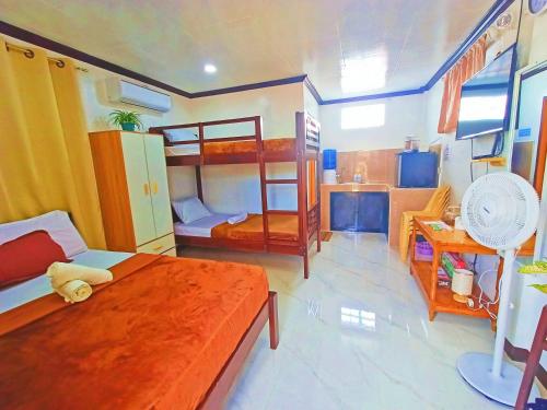 a bedroom with two bunk beds and a kitchen at Virginia Homestay, North Siargao in Burgos