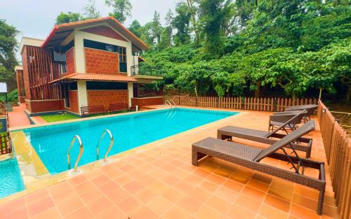 a swimming pool with two benches next to a house at Villa Katipadu Coorg in Srimangala