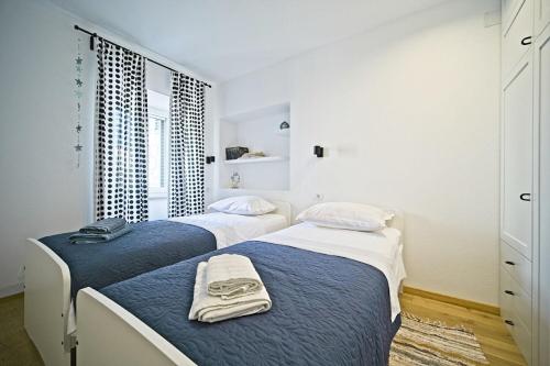 two beds in a white room with towels on them at Apartment Afitojen in Postira