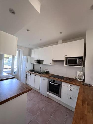 une cuisine avec des armoires blanches et des appareils électroménagers blancs dans l'établissement Spacieux T2 centre-ville Aix, à Aix-en-Provence