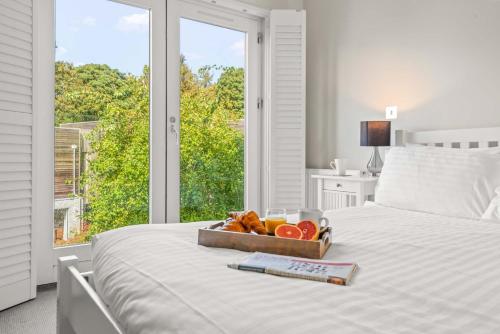 a tray of fruit on a bed with a window at House 11 in Looe