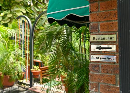 a sign on a brick wall with a plant at Proof Hotel Lekki in Lagos
