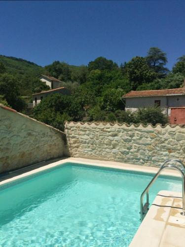 une grande piscine avec un mur en pierre dans l'établissement Maison Souquet, à Lamalou-les-Bains