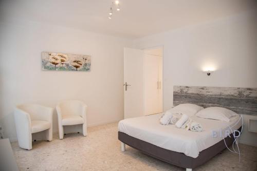 - une chambre blanche avec un lit et deux chaises dans l'établissement Spacious studio 4 minutes walk from the Beaches, à Cannes