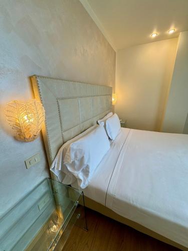 a bedroom with a large white bed with a glass table at Olivi Hotel & Natural Spa in Sirmione