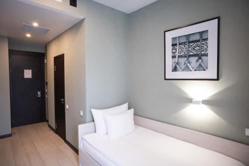 a bedroom with a white bed and a picture on the wall at Resident City Hotel in Almaty