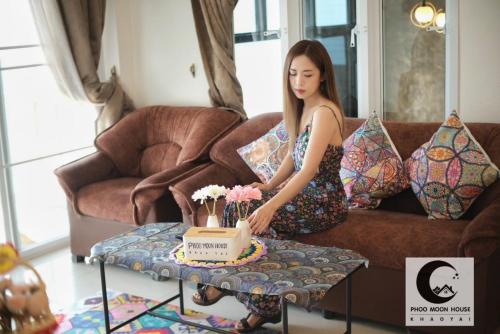 a woman sitting on a couch with a cake on a table at Phoo Moon House Khao Yai บ้านพัก ภู มูน เขาใหญ่ in Ban Bung Toei
