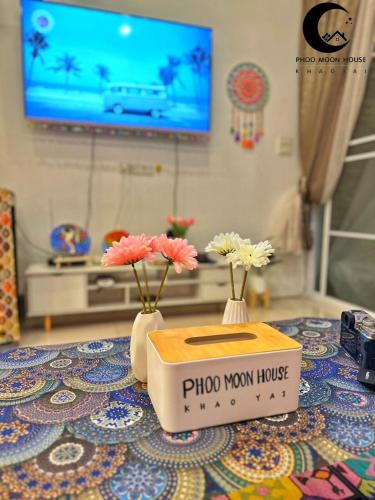 two vases with flowers on a table with a tv at Phoo Moon House Khao Yai บ้านพัก ภู มูน เขาใหญ่ in Ban Bung Toei