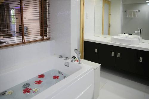 Baño blanco con bañera y lavamanos en Ripple Beach Inn, en Hulhumale