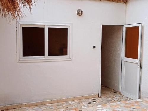 a white room with a door and a window at Auberge Chez Doki in Mbour