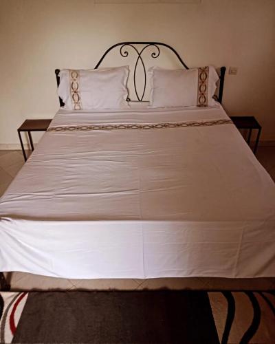 a large white bed with white sheets and pillows at Auberge Chez Doki in Mbour