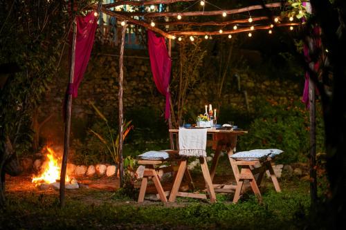 a table and chairs under a tent with a fire at SaffronStays Fairytale Villa - 3 bedroom villa in orchards and access to the river in Gushaini