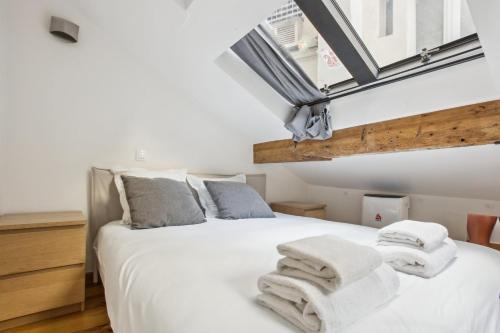 une chambre avec un lit blanc avec des serviettes dessus dans l'établissement Bluestay 131 - Charmant appartement à Paris, à Paris