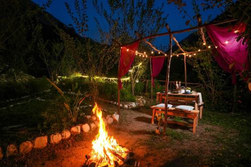 a campfire in a yard with a tent and lights at SaffronStays Fairytale Villa - 3 bedroom villa in orchards and access to the river in Gushaini