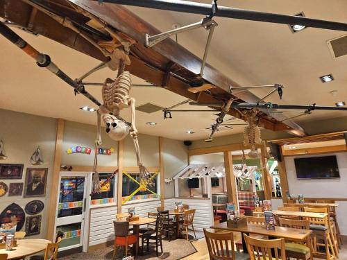 a restaurant with tables and chairs and a dinosaur hanging from the ceiling at Hiba Luxury Lodge At Parkdean Cayton Bay Holiday Park in Scarborough