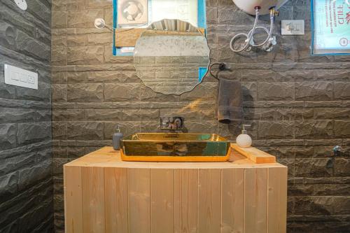 a bathroom with a yellow sink on a wooden table at SaffronStays Fairytale Villa - 3 bedroom villa in orchards and access to the river in Gushaini