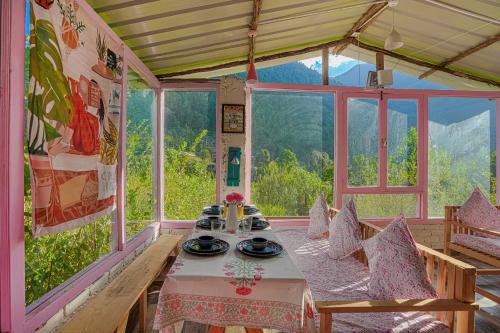 a table in a room with a view of a mountain at SaffronStays Fairytale Villa - 3 bedroom villa in orchards and access to the river in Gushaini