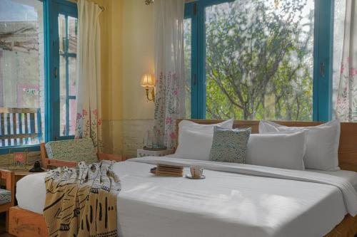 a bedroom with a large white bed with a window at SaffronStays Fairytale Villa - 3 bedroom villa in orchards and access to the river in Gushaini