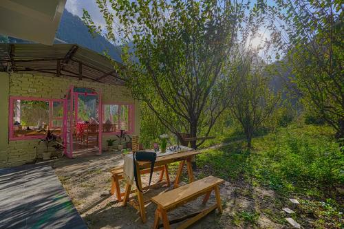 a table and a bench in front of a house at SaffronStays Fairytale Villa - 3 bedroom villa in orchards and access to the river in Gushaini