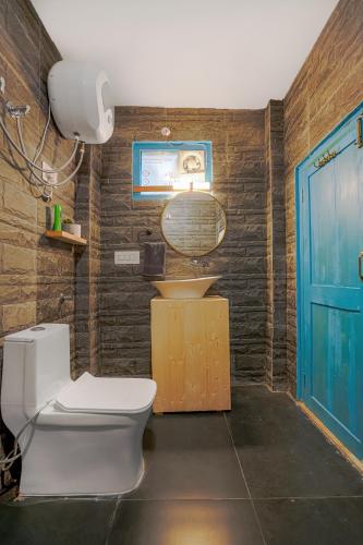 a bathroom with a toilet and a sink and a blue door at SaffronStays Fairytale Villa - 3 bedroom villa in orchards and access to the river in Gushaini