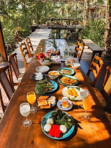 un lungo tavolo in legno con piatti di cibo sopra di Amarit Onsen Homestay a Ban Nam Ron (1)