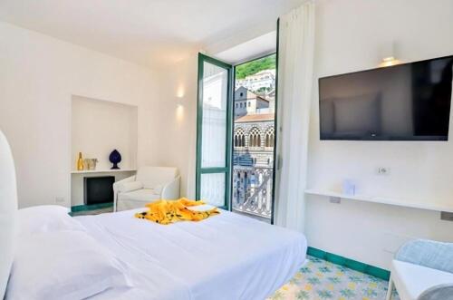 a white bedroom with a bed and a large window at Terrazza Duomo in Amalfi