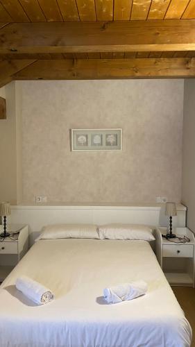 a bedroom with a white bed with two night stands at Apartamentos Panticosa in Panticosa