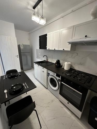 a kitchen with a stove and a washing machine at Stylish Apartment Militari - parking spot in Chiajna