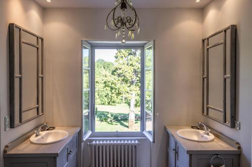 une salle de bain avec deux lavabos et une fenêtre dans l'établissement La Chartreuse des Ormeaux maison de maître en Dordogne, à Saint-Alvère