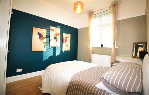 a bedroom with a bed and a blue wall at Large Bungalow - Sleeps 8 - 3 Large Beds - Plus Sofa Bed - Off Street Parking - Very Large Enclosed Gardens - Fast Wifi in Birmingham