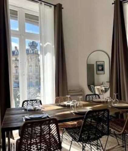 une table de salle à manger avec des chaises et une grande fenêtre dans l'établissement Casa Kûta - Place de la Comédie, Montpellier, à Montpellier
