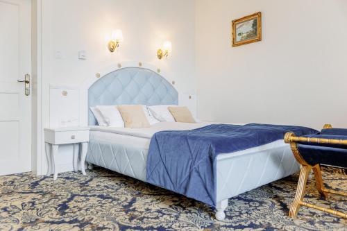 a bedroom with a large bed with a blue headboard at Dwór Prezydencki Boutique Hotel & SPA in Tarnów