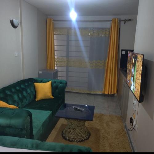 een woonkamer met een groene bank en een tafel bij Jessy stays in Nairobi