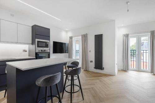 a kitchen with a counter and two stools at Modern Brixton Apartments in London