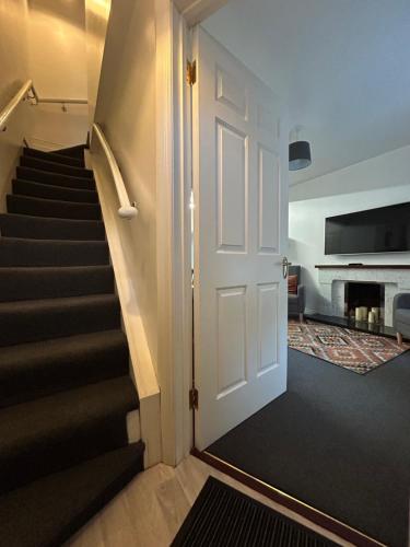 a hallway with a white door and stairs with a fireplace at Central Town House, Moville in Moville