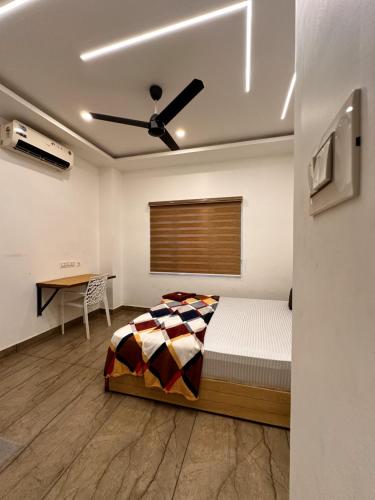 a bedroom with a bed and a table and a ceiling fan at Grandstaykannur in Kannur