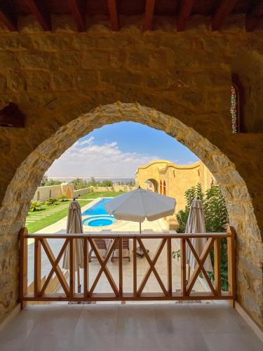 an arch in a wall with a table and an umbrella at Hoopoe lodge in Tunis