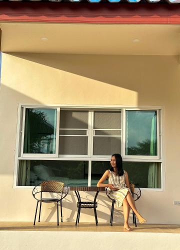 a woman sitting on a bench in front of a window at JJ and J Garden1 Pai in Pai