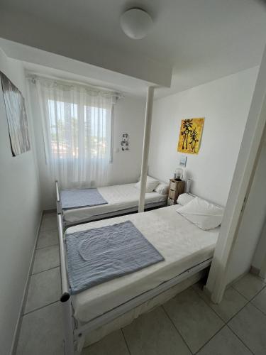 deux lits dans une chambre avec une fenêtre dans l'établissement L'Aigue Marine, à Saint-Jean-de-Monts