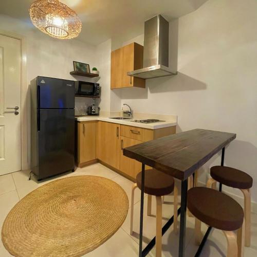 a kitchen with a black refrigerator and a table at 1 Bedroom Penthouse 3BEDS Sunset & City lights with big balcony FREE ACCESS to all amenities in Manila