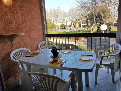 une table bleue avec des chaises blanches, une table et une fenêtre dans l'établissement Proche du centre commercial des Capellans joli T2 mezzanine avec parking - 4OLI76, à Saint Cyprien Plage