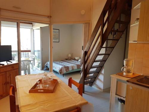 - une cuisine avec une table à manger et un escalier dans une pièce dans l'établissement Proche du centre commercial des Capellans joli T2 mezzanine avec parking - 4OLI76, à Saint Cyprien Plage
