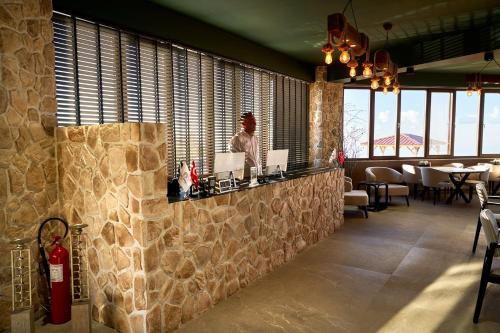 a woman sitting at a bar in a restaurant at Flora Handüzü Resort & Wellness Bungalow Hotel in Rize